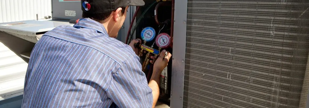 HVAC technician servicing a condenser unit in Liberty
