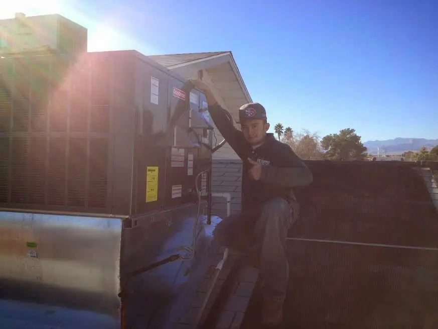 HVAC technician performing Boiler Repair on a rooftop unit in Liberty